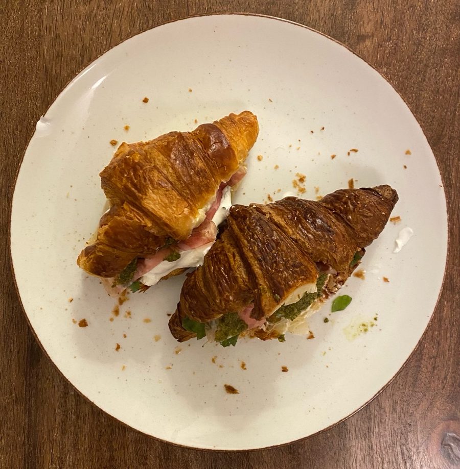 Croissant z burratą i szynką długodojrzewającą — gotowe danie na talerzu, zdjęcie z góry